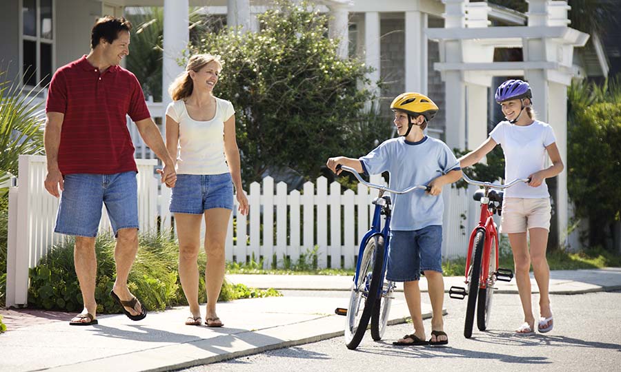 family walking and riding bikes in neighborhood