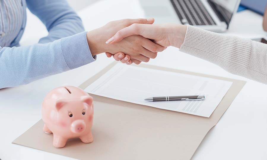 Piggy bank on desk. Banker and customer shaking hands